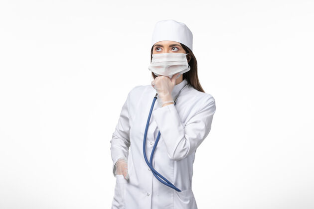 人正面图：女医生穿着白色无菌医疗服 戴着口罩 因为柯维德-思考白墙疾病柯维德-大流行病毒疾病正面病毒男性