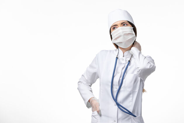 疾病正面图女医生身穿白色无菌医疗服 带口罩 因白墙上有冠状病毒病大流行到期大流行人