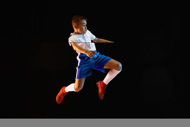 活动小男孩像个足球运动员一样站在黑暗的墙上目标球身体