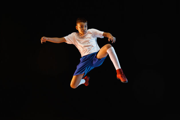 比赛小男孩像个足球运动员一样站在黑暗的墙上分数活动足球