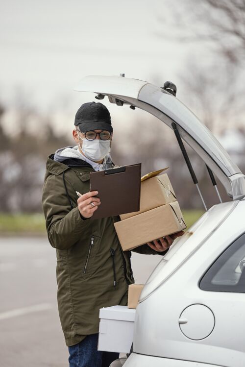 男带着面具和包裹的男性送货员外科口罩送货服务男人