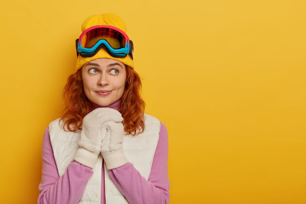 黄色人 娱乐 思想 休闲活动的概念可爱的姜女双手放在胸前 穿着暖和的衣服 滑雪面罩 想着冬天的新冒险寒冷成人高兴