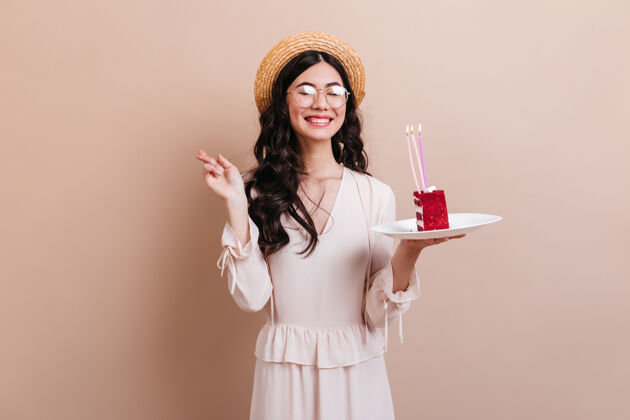 生活方式可爱的亚洲女人一边笑一边许生日愿望优雅的日本女人戴着帽子拿着一块蛋糕情感韩国人面包房