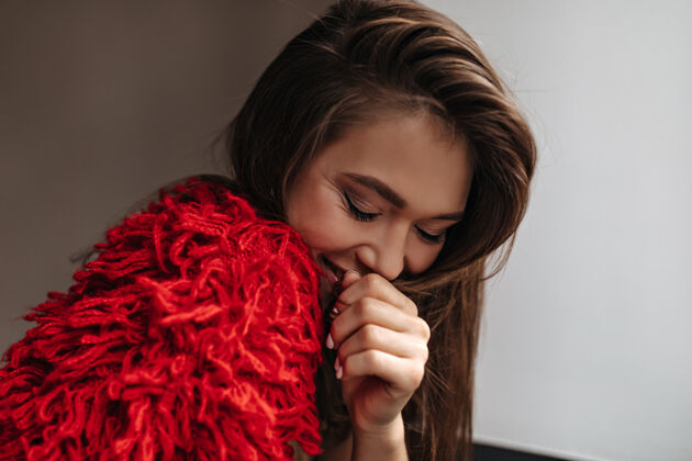 羊毛一个害羞的女人 穿着鲜红的羊毛衫 微笑着 在白色的背景下捂着嘴情感漂亮里面