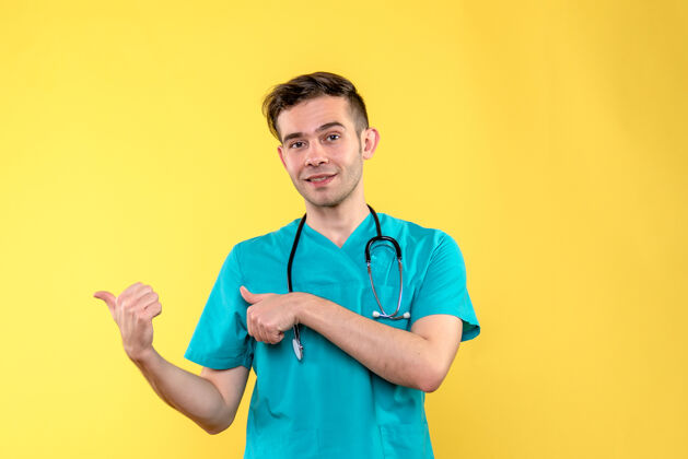 人黄色墙上微笑的年轻男医生的正面图听诊器正面病毒