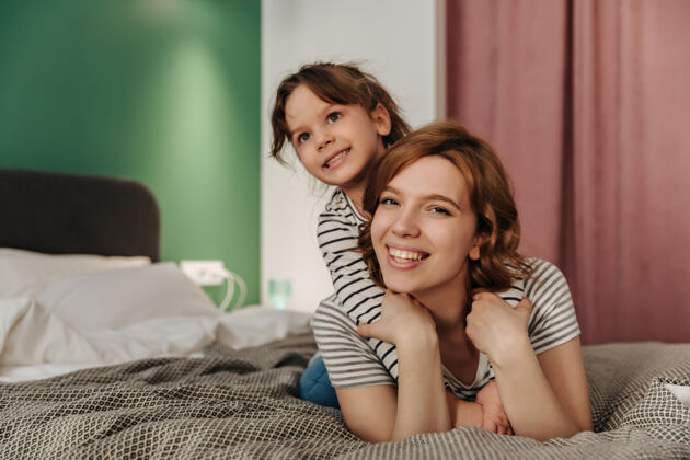 生活方式积极的妈妈和女儿玩得开心 拥抱和躺在床上在一起妈妈室内