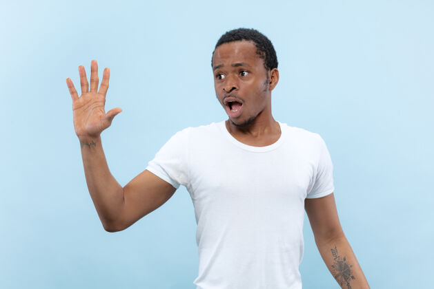 会议半身特写肖像的年轻非洲裔美国男子在白色衬衫的蓝色空间人类的情感 面部表情 广告 销售理念商人成功衬衫