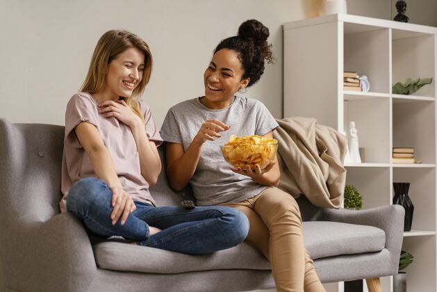 房子坐在沙发上看电视吃薯片的女人看电视零食女人