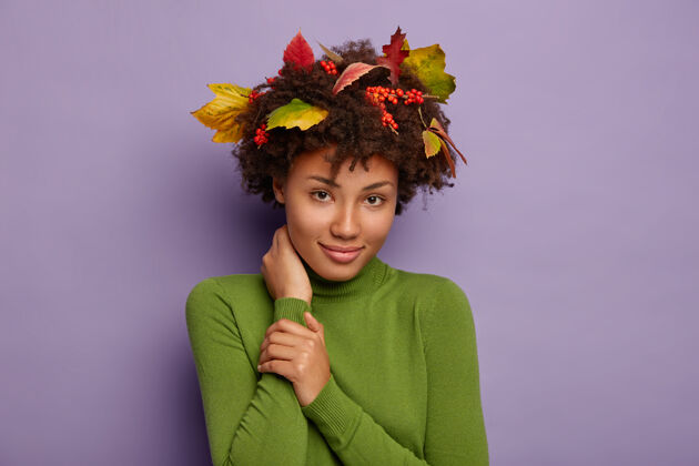水平可爱的非洲裔美国女士的肖像触碰脖子 冷静地看着相机 穿着休闲的马球衫 秋天的树叶 浆果在卷发完美的发型满意室内脖子马球衫