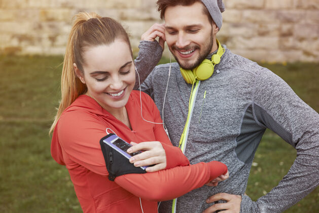 运动训练快乐的年轻夫妇用耳机听音乐活动帽子看