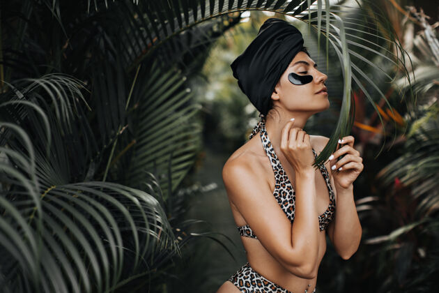 森林性感的穿着泳装的年轻女子站在异国情调的背景上戴着眼罩的女士在棕榈树旁摆姿势的户外镜头户外棕榈树异国情调