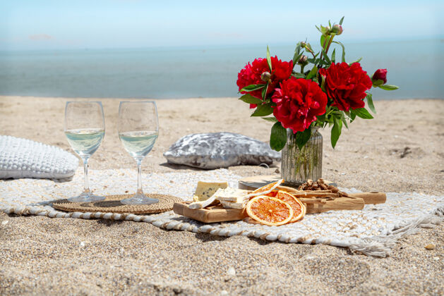酒精浪漫的沙滩野餐 香槟 小吃和鲜花度假和浪漫的概念大海小吃鲜花