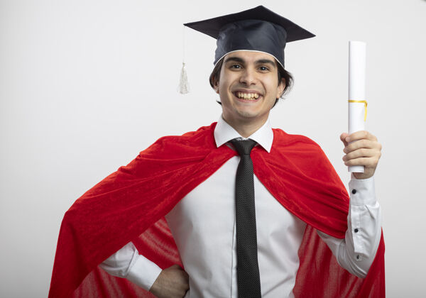 穿带着微笑的年轻超级英雄戴着领带和毕业帽拿着毕业证书 手放在臀部超级英雄小伙子领带