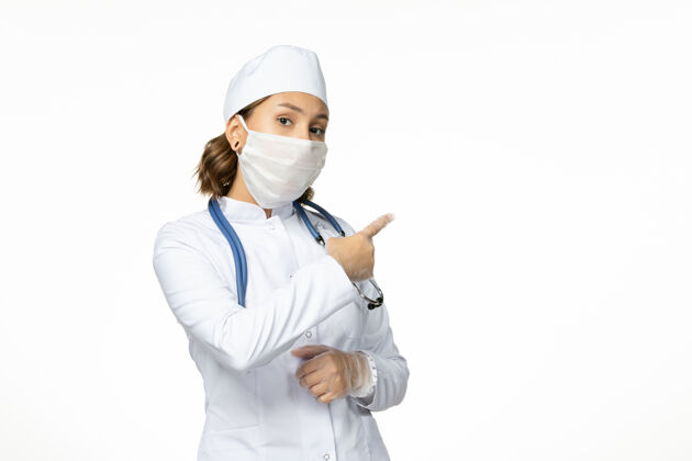 办公桌白色办公桌上戴着无菌口罩的年轻女医生病毒大流行到期