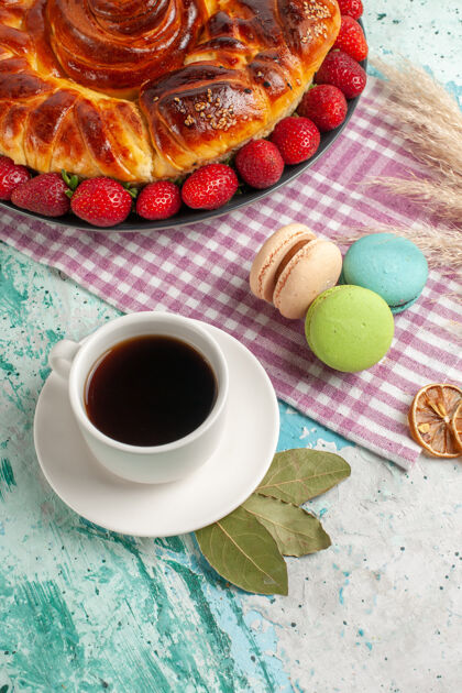餐俯瞰美味的派与红色草莓和一杯茶在蓝色的表面饼干顶蛋糕