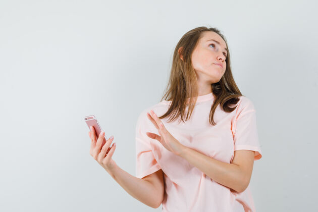 手机穿着粉色t恤拿着手机的年轻女孩 看起来很恼火 正对着前方快乐孩子电话