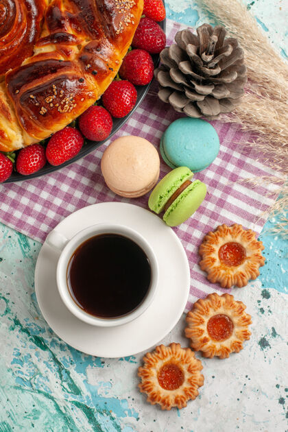 饼干顶视图草莓派饼干马卡龙和一杯茶在蓝色的表面生的杯子餐