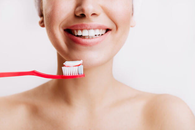 牙膏带着真诚微笑的女孩每天早上都会在隔离的墙上刷牙年轻皮肤护理成人