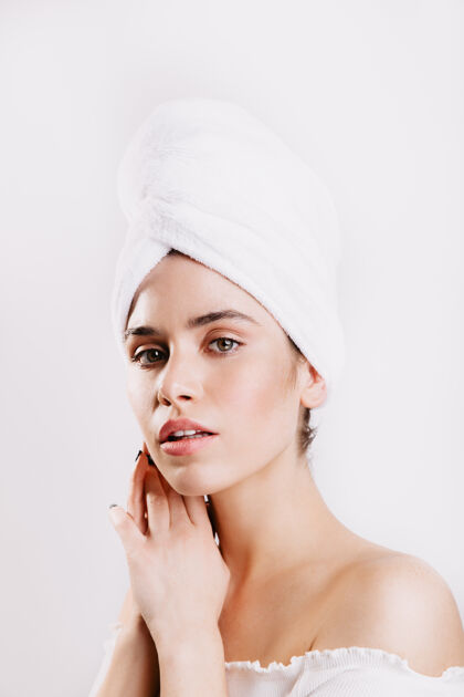 成人完美皮肤的绿眼睛女人头上戴着毛巾在白墙上摆姿势脸女孩淋浴
