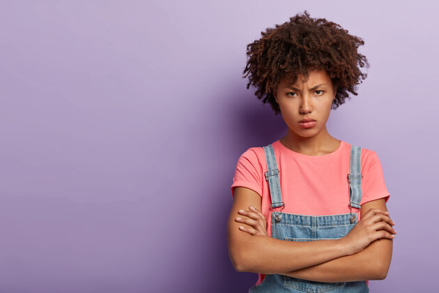 人不满的愤怒的年轻女子与一个穿着工作服的黑人摆姿势的肖像姿势冒犯随意