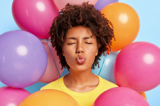 发型特写镜头美丽的年轻女子摆姿势周围的生日彩色气球室内快乐亲吻