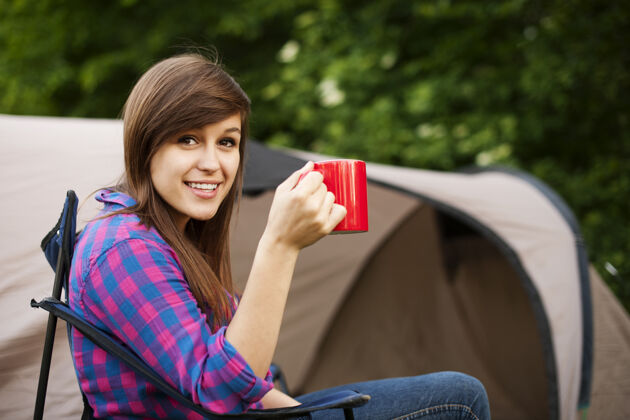 休息坐在帐篷前的年轻女子人坐着喝酒