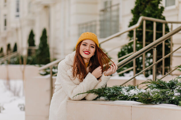时尚可爱的戴着帽子的姜黄色女孩表达积极的情绪美丽的女模特在冬天放松外套冬天寒冷的天气