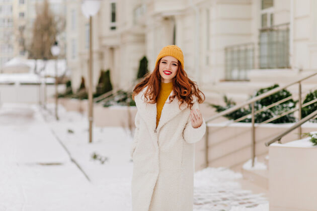 外套一月份 美丽的少女微笑着摆姿势笑着的姜姑娘的冬季肖像城市帽子女性