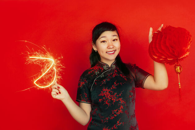 年手捧火花和灯笼新年快乐红色背景上的亚洲少女肖像身着传统服装的女模特看起来很快乐复制空间文案空间微笑红色