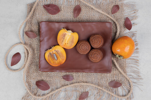 糕点巧克力饼干和柿子片放在盘子里高质量的照片面包店水果巧克力