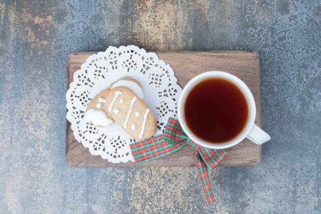 圣诞节两个圣诞饼干和一杯茶在木板上高品质的照片饼干糕点面包店