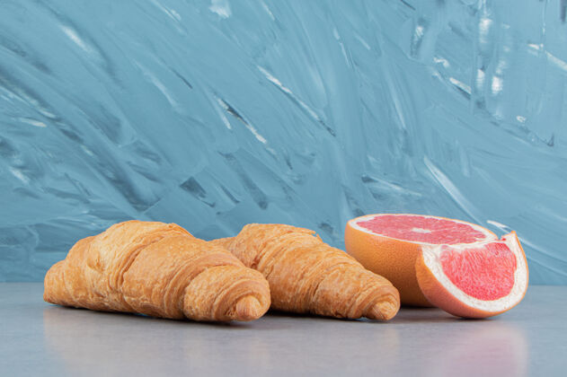 葡萄柚蓝色背景上的西柚片和羊角面包高品质照片巧克力糖美味