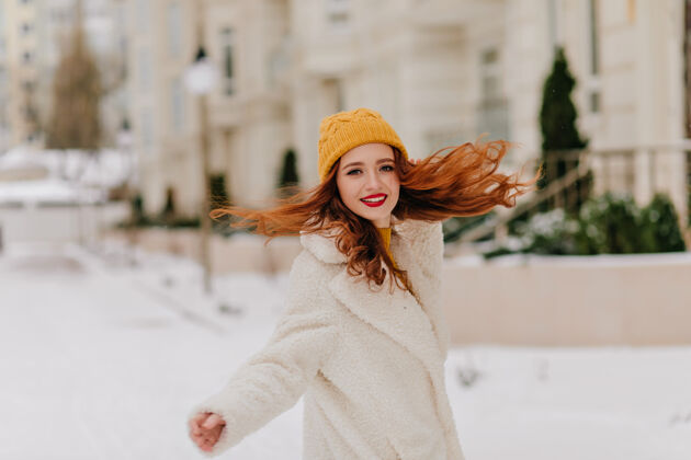 冬天可爱的女孩 长长的卷发在雪地上翩翩起舞可爱的穿着外套的女模特在冬天玩得很开心雪欧洲欢呼