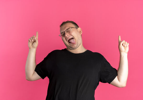目录一个戴眼镜的胖男人穿着黑色的t恤 正开心地伸出舌头 用食指指着粉色的墙壁穿乐趣舌头
