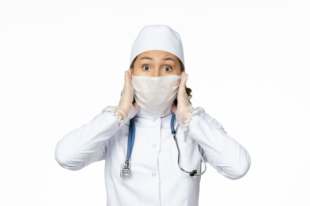 制服正面图年轻女医生 穿着白色医疗服 戴着口罩 因为浅白色表面有冠状病毒医生到期浅白色