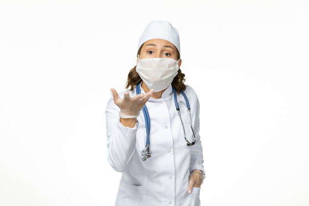 冠状病毒正面图：年轻女医生戴着无菌口罩和防护手套 白色办公桌上有冠状病毒手套医生办公桌