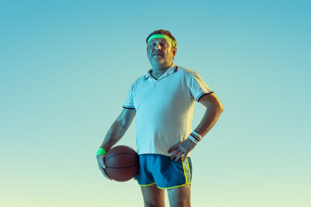 动作高级男子在霓虹灯下的梯度背景下打篮球身材魁梧的白种人男模保持活跃 运动精神教练欢呼男性