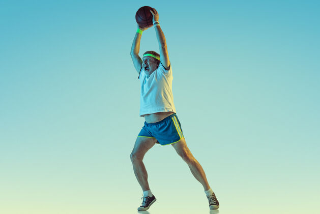 爱好高级男子在霓虹灯下的梯度背景下打篮球身材魁梧的白种人男模保持活跃 运动精神文案空间霓虹灯单身