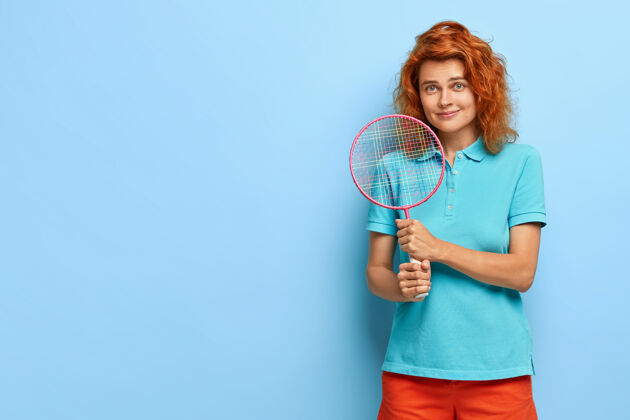 室内漂亮的姜黄色女人 卷发 喜欢网球 拿着球拍 准备打球 穿着休闲夏装姿势白种人红发