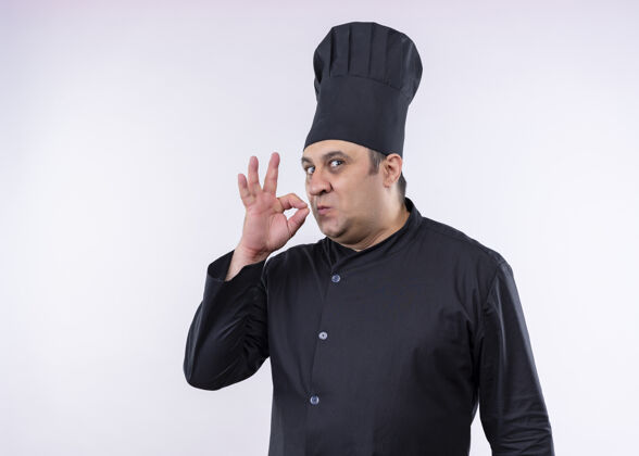 制服男厨师身穿黑色制服 头戴厨师帽 站在白色背景上 展示美味的标志标志展示帽子