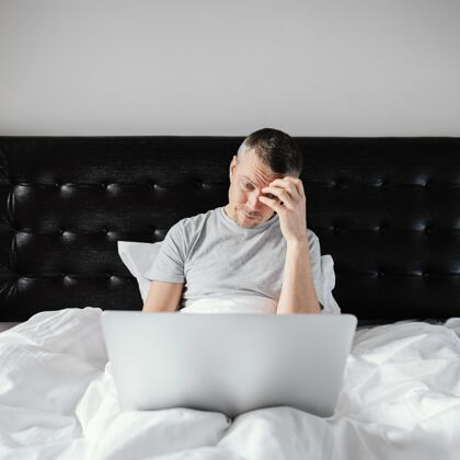 设备男人在床上用笔记本电脑笔记本电脑男人卧室
