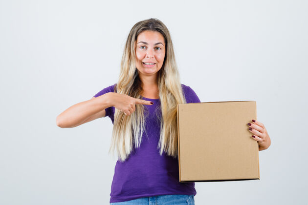 年轻年轻女性指着紫罗兰色t恤的盒子 目光专注前视图成人指向休闲