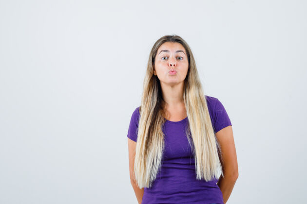 美丽年轻女性在紫罗兰色t恤前视图中撅起嘴唇灰色休闲女性