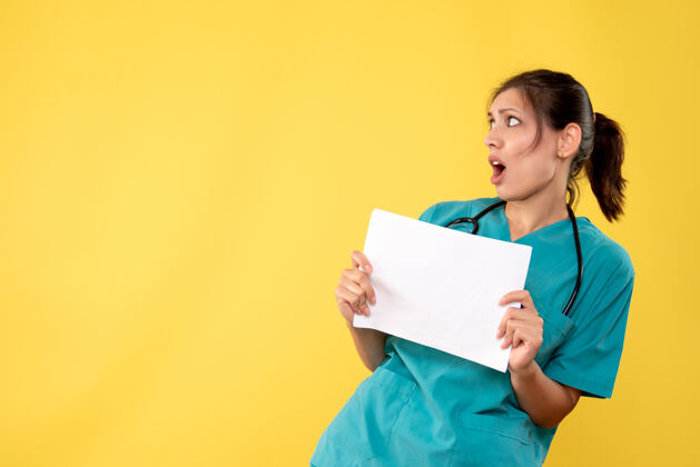视图正面图年轻女医生穿着医用衬衫拿着黄色背景的纸张分析纸医学肖像