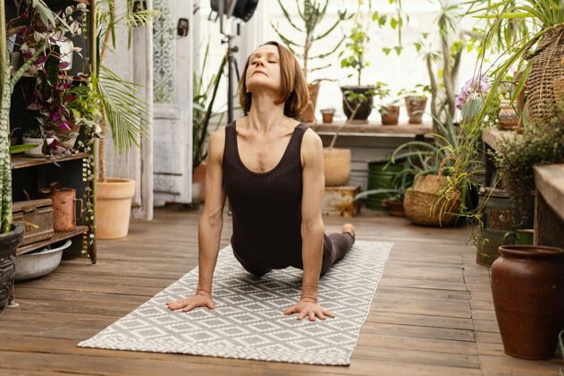 植物在垫子上做瑜伽的全镜头女人高级活跃训练
