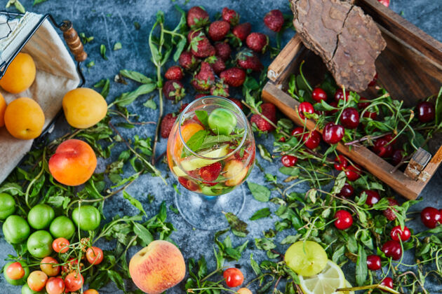 花园红色的新鲜樱桃放在木箱里 一杯果汁和新鲜水果玻璃成熟杏子