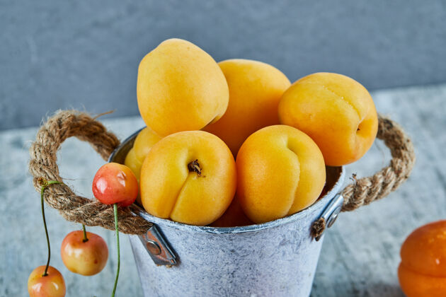 餐桌美味的熟杏子放在铁桶里 樱桃放在大理石表面夏天食物健康