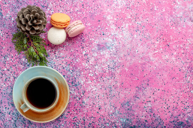 小俯瞰法国麦卡龙美味的小蛋糕与茶杯粉红色的表面热的马克杯烘焙