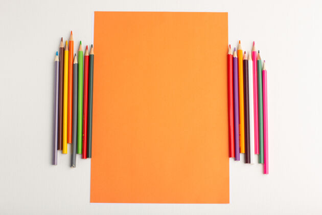 顶部顶视图橙色空白纸 白色表面上有彩色铅笔教育绘画彩色