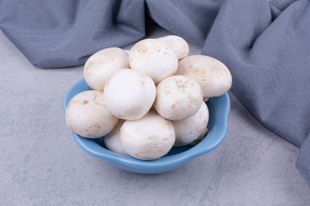 品质白蘑菇在地上的蓝碗里桌布季节美味